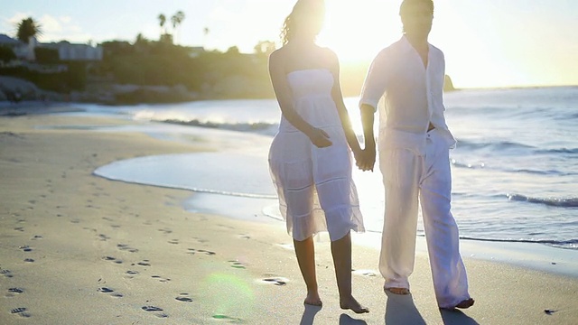 一对夫妇手牵着手离开夕阳下的海滩视频素材