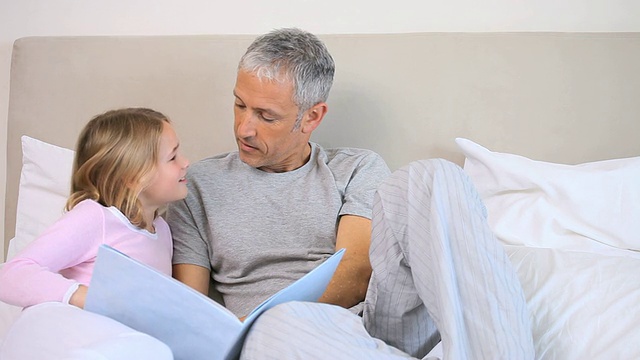 微笑的女孩和她的父亲读一本书视频下载