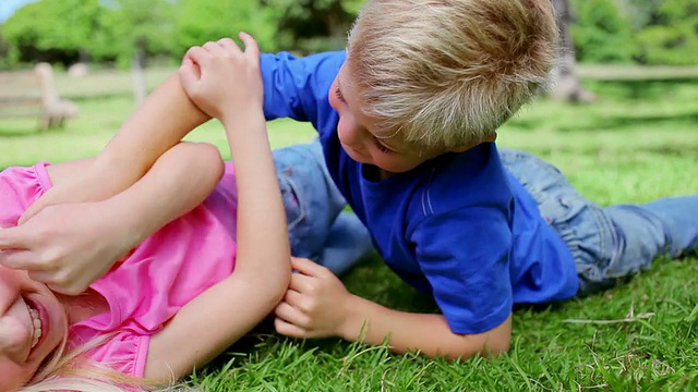 男孩和女孩在草地上互相挠痒痒视频素材