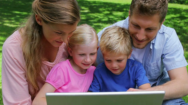 一家人坐在一起使用笔记本电脑，然后看着镜头微笑视频素材