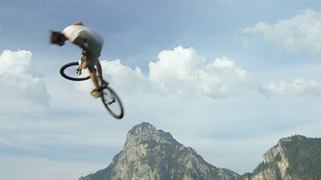 慢动作购买表演特技与自行车跳进特朗西湖;背景是特劳斯坦山视频素材