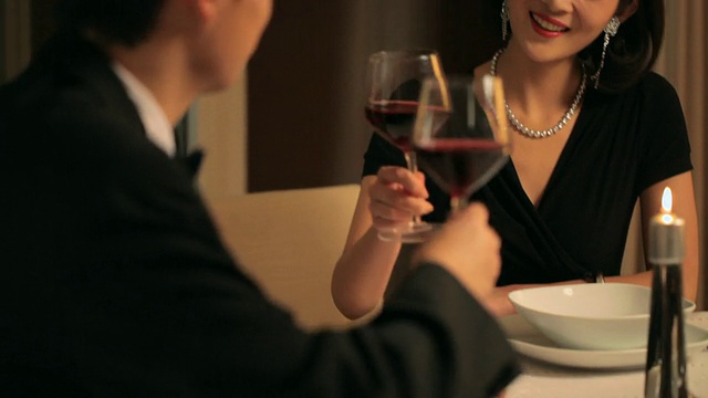 在烛光晚餐/中国，一对夫妇用酒杯敬酒视频下载