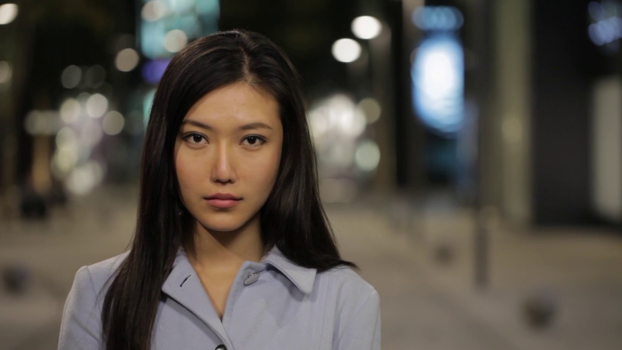CU晚上城市街道上年轻女子对着镜头微笑的肖像/中国视频下载