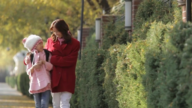母亲和女儿在人行道上散步聊天/中国视频素材