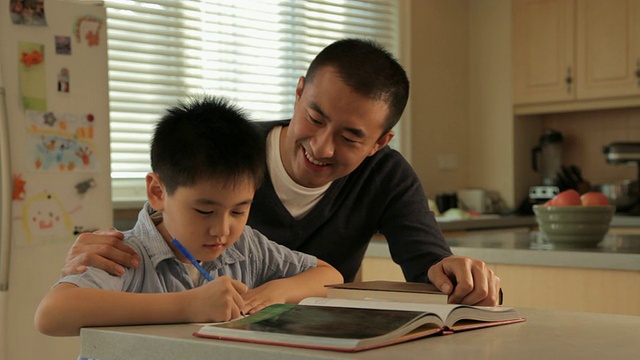 父亲在厨房/中国帮助儿子做作业视频素材