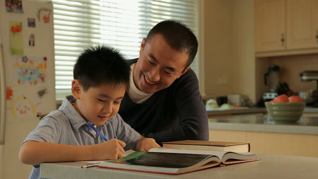 父亲在厨房/中国帮助儿子做作业视频素材