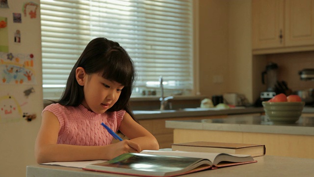 年轻女孩在厨房做家庭作业/中国视频素材