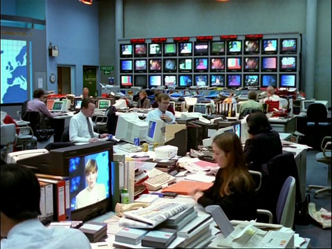 档案时间流逝-在电视新闻室工作的人，在背景的电视屏幕银行视频下载