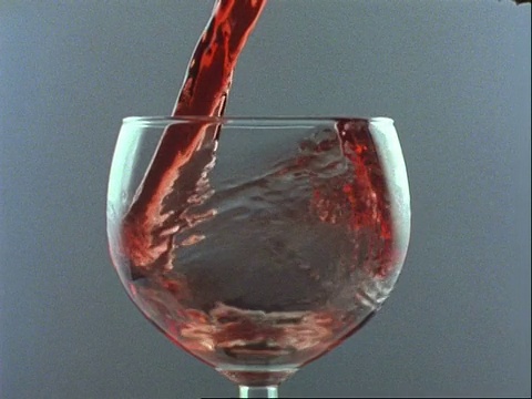 高速铜红葡萄酒倒入圆形玻璃杯，灰色背景视频素材