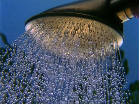 高速的水滴从喷壶落下，背景是树叶视频下载