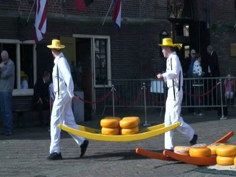 荷兰阿尔克马尔历史悠久的奶酪市场上，人们拿着大轮奶酪视频下载