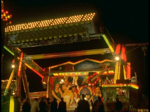 T/L游乐场在夜晚-霓虹照明游乐场的游乐，旋转，旋转游乐对黑色的天空视频下载
