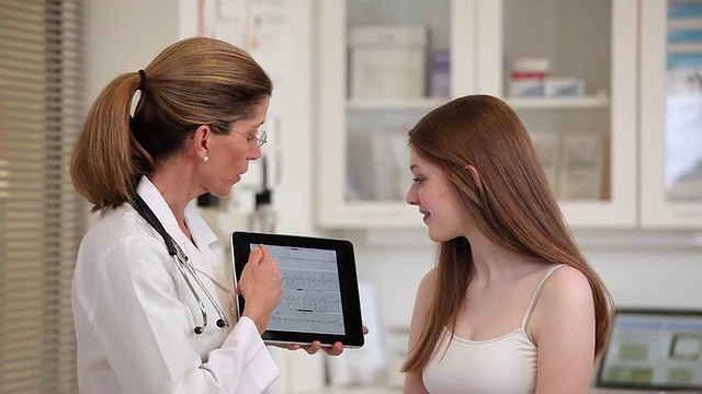美国维吉尼亚州里士满诊所的医学博士向青少年病人展示平板电脑的医学测试结果视频购买