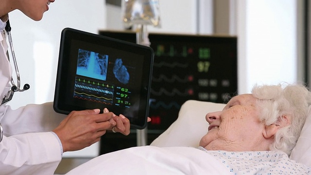 CU TD医生在病床上与老年患者交谈，展示患者平板电脑测试结果/ Richmond, Virginia, USA视频下载
