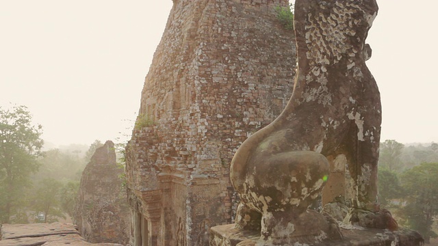 日出时，柬埔寨暹粒吴哥窟的僧侣们走在森林中一座古老寺庙的顶端视频素材