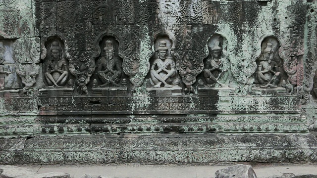 柬埔寨暹粒，一名佛教僧侣走过一堵雕刻复杂的石墙视频素材