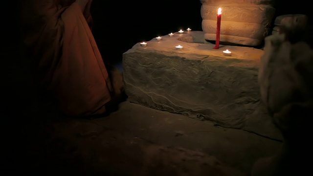 在柬埔寨暹粒吴哥窟的一座古庙里，一名和尚正在向一尊点燃蜡烛的佛像祈祷视频素材