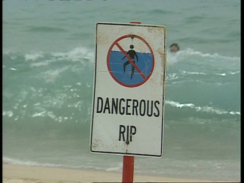 CU海滩标志危险撕裂，背景中有人正在登船视频下载