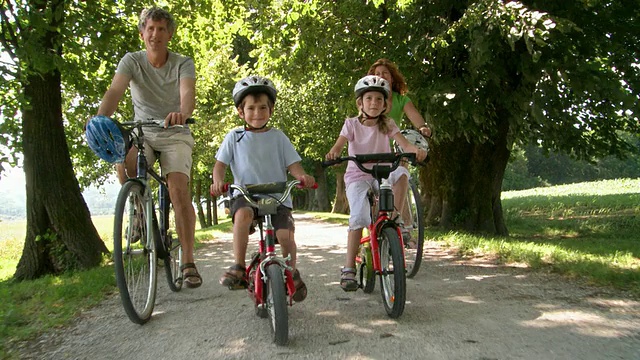 家庭和两个孩子在公园里骑自行车视频素材