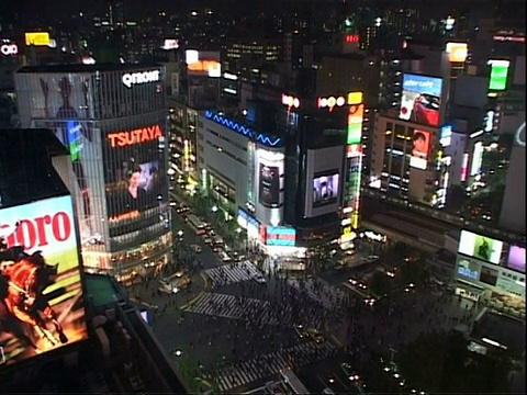 高角度观看拥挤的十字路口在晚上，周围的建筑标志，广告牌和视频屏幕，东京视频素材