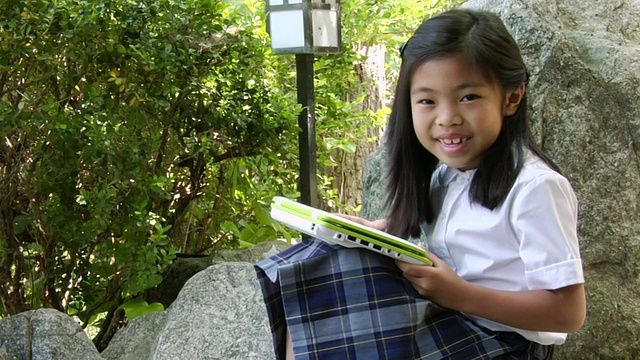 MS小女孩使用白色绿色笔记本电脑在公园和微笑/洛杉矶，加利福尼亚，美国视频下载