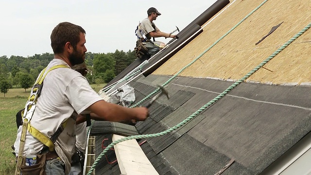 美国密歇根州切尔西市，三名工人在一幢红色建筑的屋顶上敲打视频下载