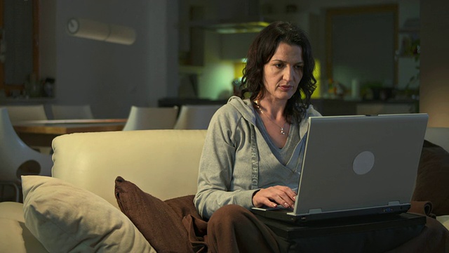 女人在晚上用笔记本电脑工作视频素材