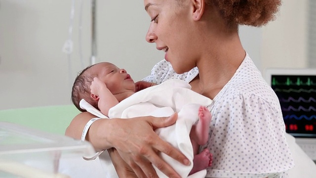 美国弗吉尼亚州里士满医院，母亲抱着新生婴儿低声耳语视频素材