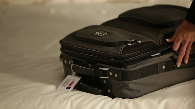 一名女子在卧室里关闭行李箱拉链/美国加州洛杉矶视频素材
