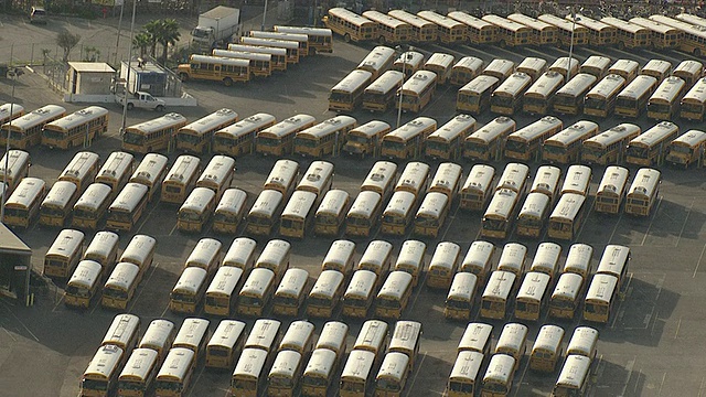 宽镜头空中推出-一排排的校车在停车场排成一行。/美国加州洛杉矶视频下载