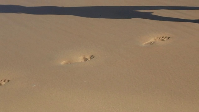 沙子留下的脚印被海浪冲走了视频素材