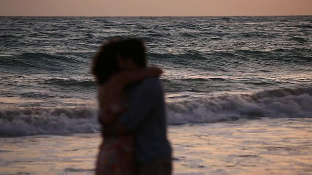 漂亮的年轻夫妇拥抱在日落前的大海视频素材