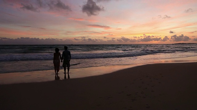 漂亮的年轻夫妇在海边散步在日落视频素材