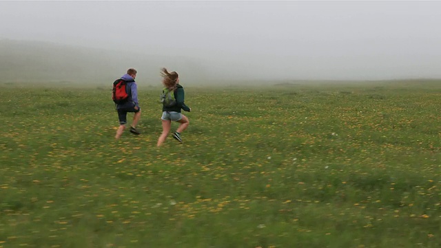 多丽视图的青少年跑步通过雾蒙蒙的山地草地视频下载