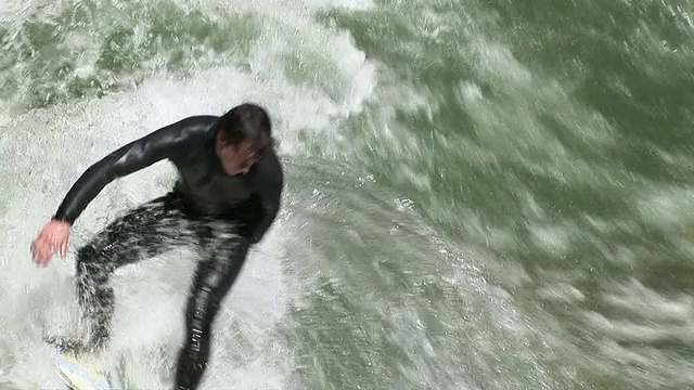 在英国花园/德国巴伐利亚慕尼黑，冲浪者在他的冲浪板和波浪的“Eisbach”溪视频素材