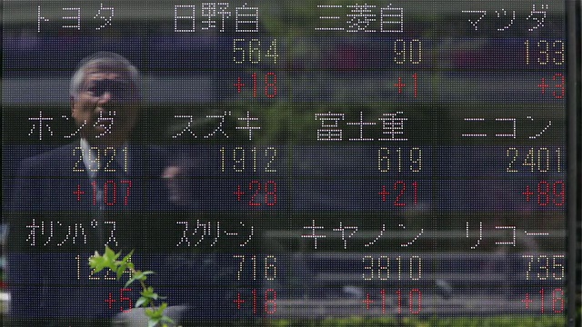 在日本东京商业区，一名男子在一个巨大的显示屏上观察股票价格的变化视频下载