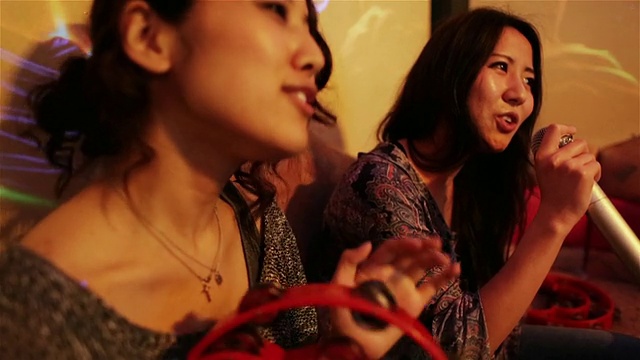在日本东京的一家卡拉ok俱乐部里，女孩们一边唱歌一边慢慢地摇着小手鼓视频下载