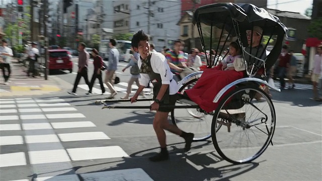 一名人力车车夫拉着一辆jinrikisha穿过东京街道/日本东京视频下载