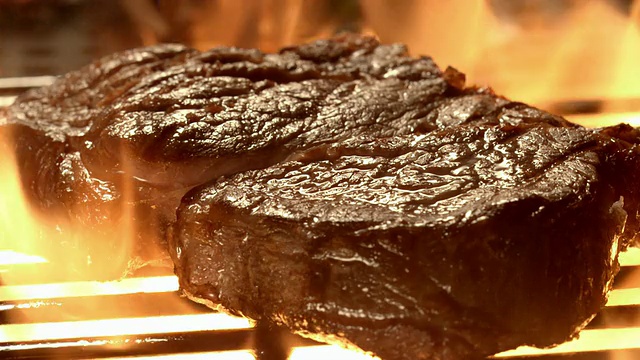 将CU牛排放在明火烤架上，火焰在肉的四周喷射视频下载