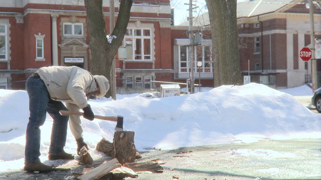 在加拿大安大略省多伦多市的冬日里，一名年轻男子决定用他的斧头砍木头视频素材