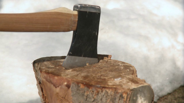 加拿大，安大略省，多伦多，一名男子用脚将斧头从木头上移开，然后砍木头视频素材