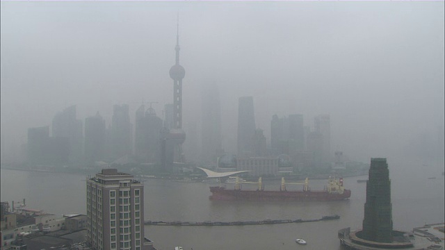 一艘货船驶过北京市中心被雾霾笼罩的摩天大楼。中国/北京视频下载