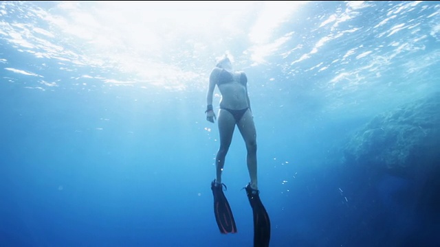 西班牙伊比沙岛，一名女子漂浮在湛蓝的海水中，来到阳光下视频下载