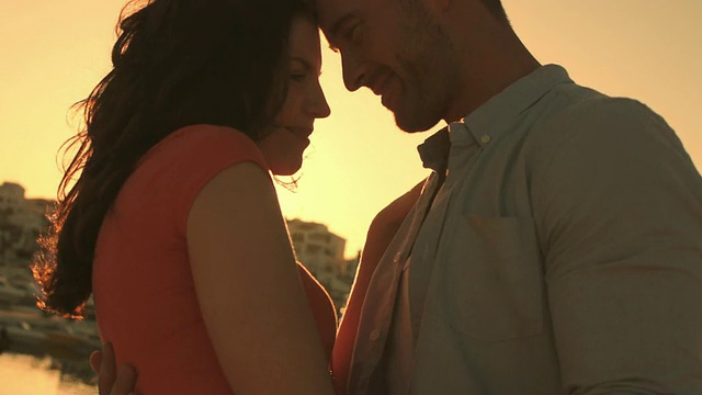 一对年轻夫妇在夕阳中在码头旁跳舞。视频素材