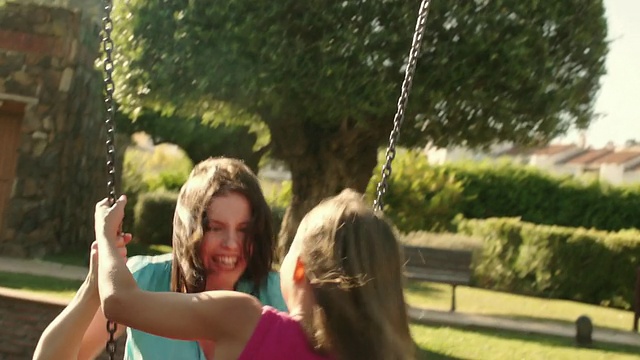 慢镜头:一家人在公园里，母女荡秋千。视频素材