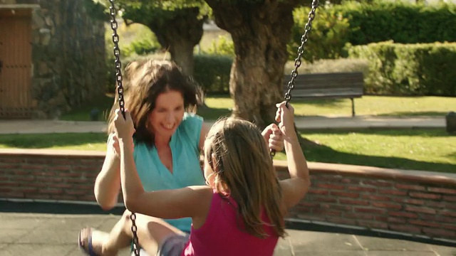 一家人在公园，妈妈和女儿在荡秋千。视频素材