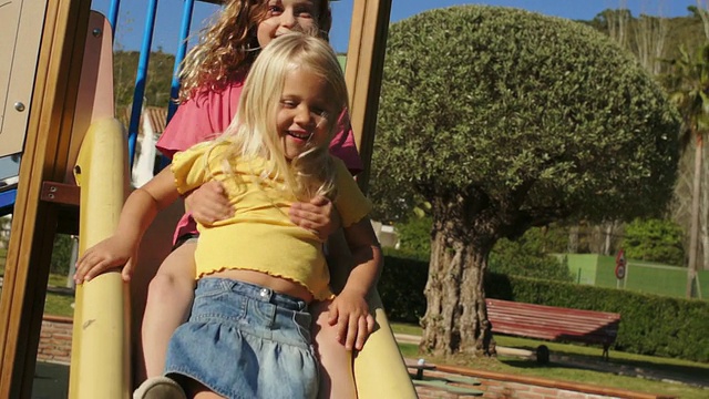 两个孩子在公园里玩滑梯。视频素材