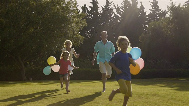 孙子和爷爷奶奶拿着气球跑到花园里拍照。视频素材