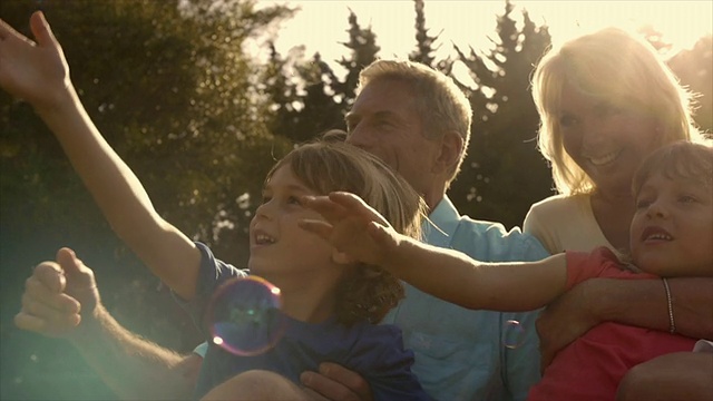 孙辈和祖父母在花园里玩泡泡的慢镜头。视频素材