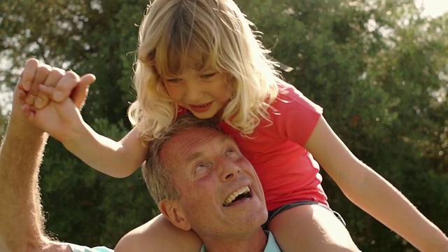 爷爷和孙女在花园的肩膀上玩。视频下载